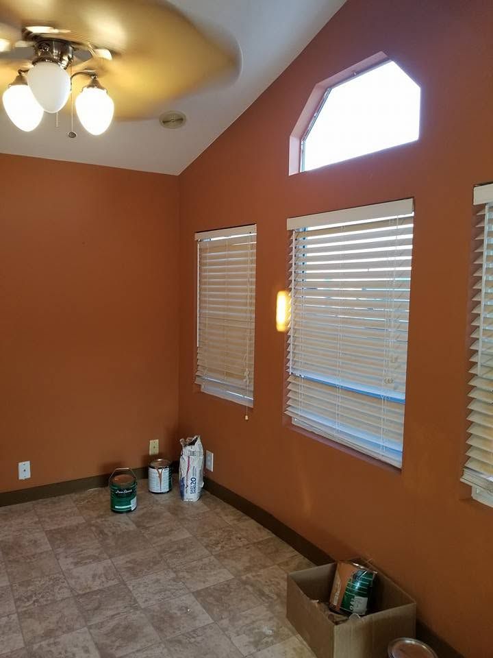 Orange room with tiled floor, ceiling fan, and windows with blinds and a small high window.