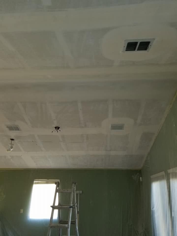 Room with green walls, ladder, and unfinished white ceiling with vents and lights