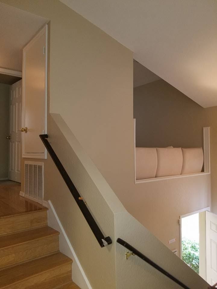 Stairway with wooden steps, black handrails, and a beige wall beside a small landing window.