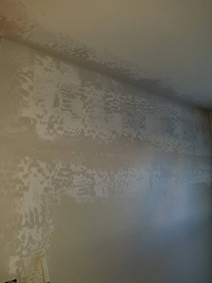 Close-up of a textured beige wall with peeling paint and light reflection near a corner