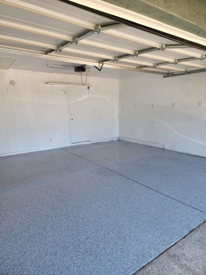Empty garage with white walls, open garage door tracks, and speckled gray floor.