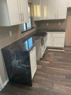 Small kitchen with white cabinets, dark countertops, and wood-look flooring.