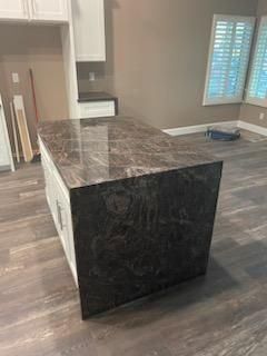 Kitchen island with dark marble countertop and black side panels in a partially furnished room