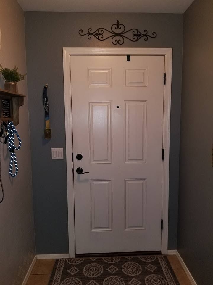 Front entryway with a white door, gray walls, decorative metal wall art, and a patterned rug.