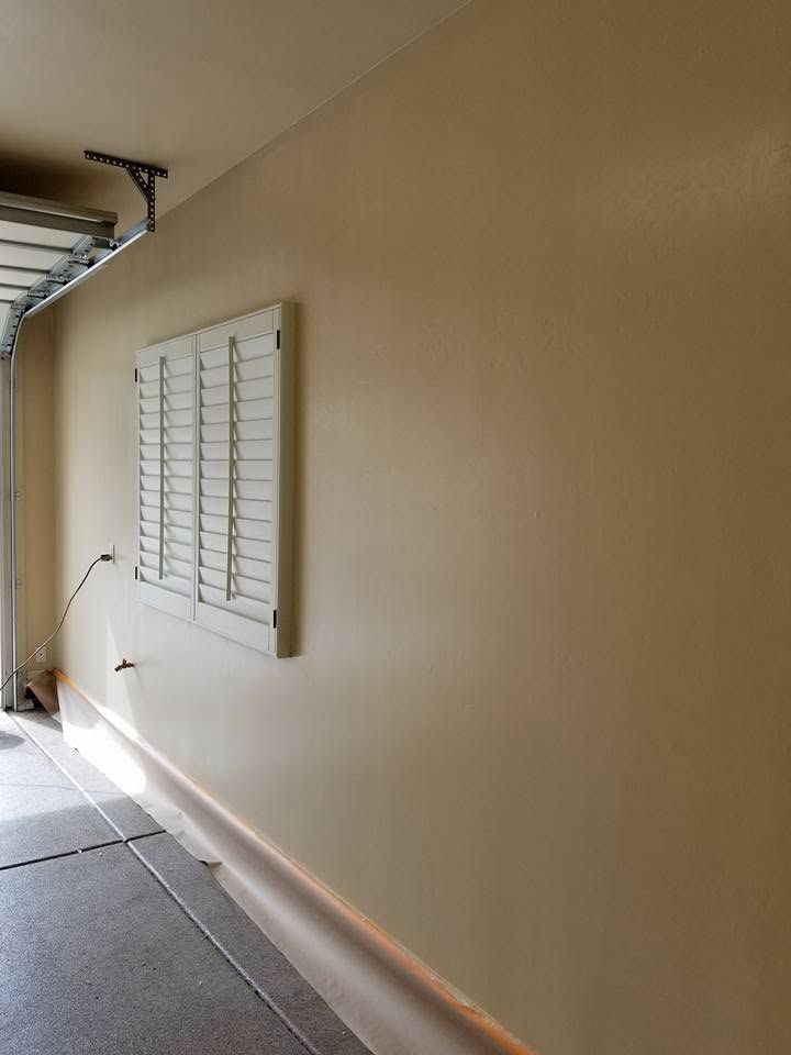 Exterior apartment walkway with beige wall, windows, and a narrow concrete floor corridor.