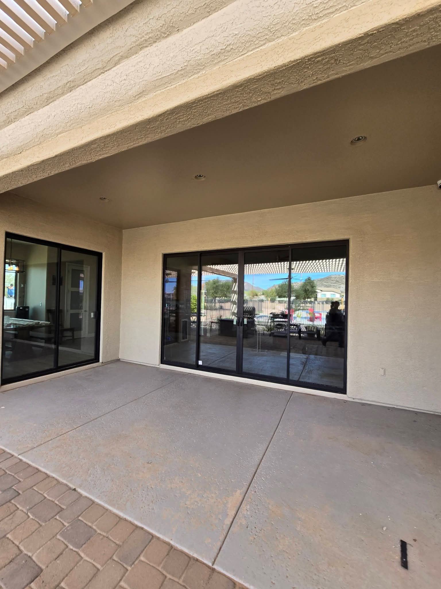 Covered patio with sliding glass doors and a brick-paver walkway in front of a building
