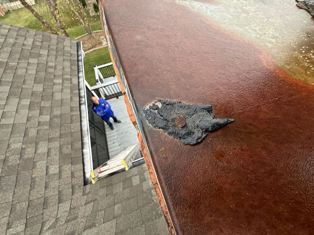 A man is sitting on the roof of a house.