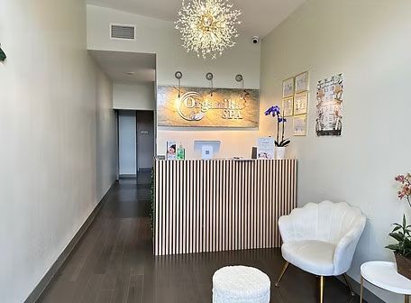 Modern reception area with striped desk, white chairs, dark wood floor, and pendant lights.