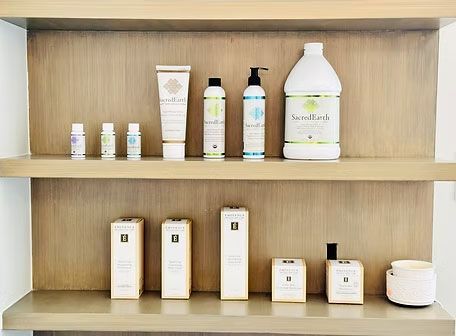 Wooden display shelf with neatly arranged skincare bottles, tubes, and jars on two shelves.