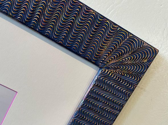Close-up of a blue picture frame with wave-like pattern and gold highlights.