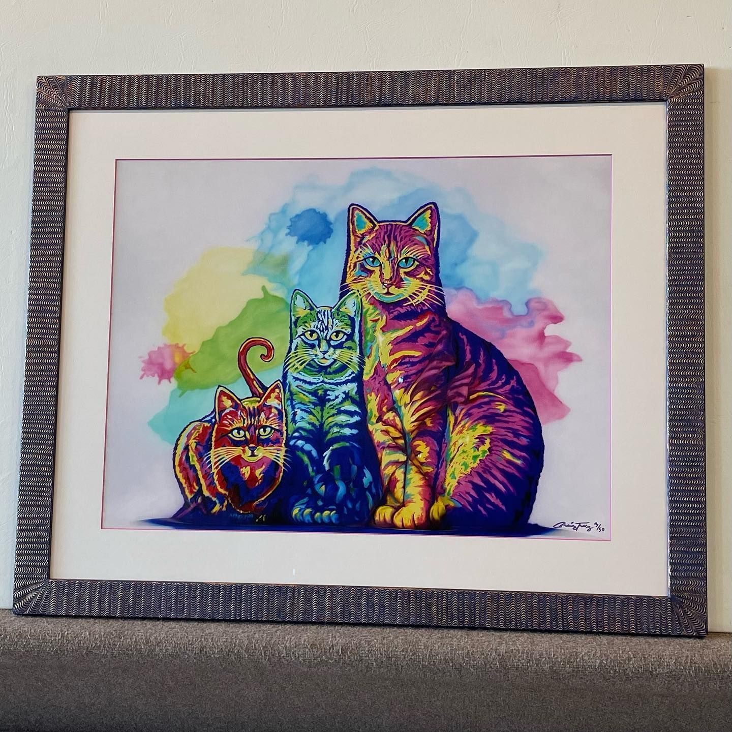 A vibrant, rainbow-colored cat family portrait in a decorative frame.