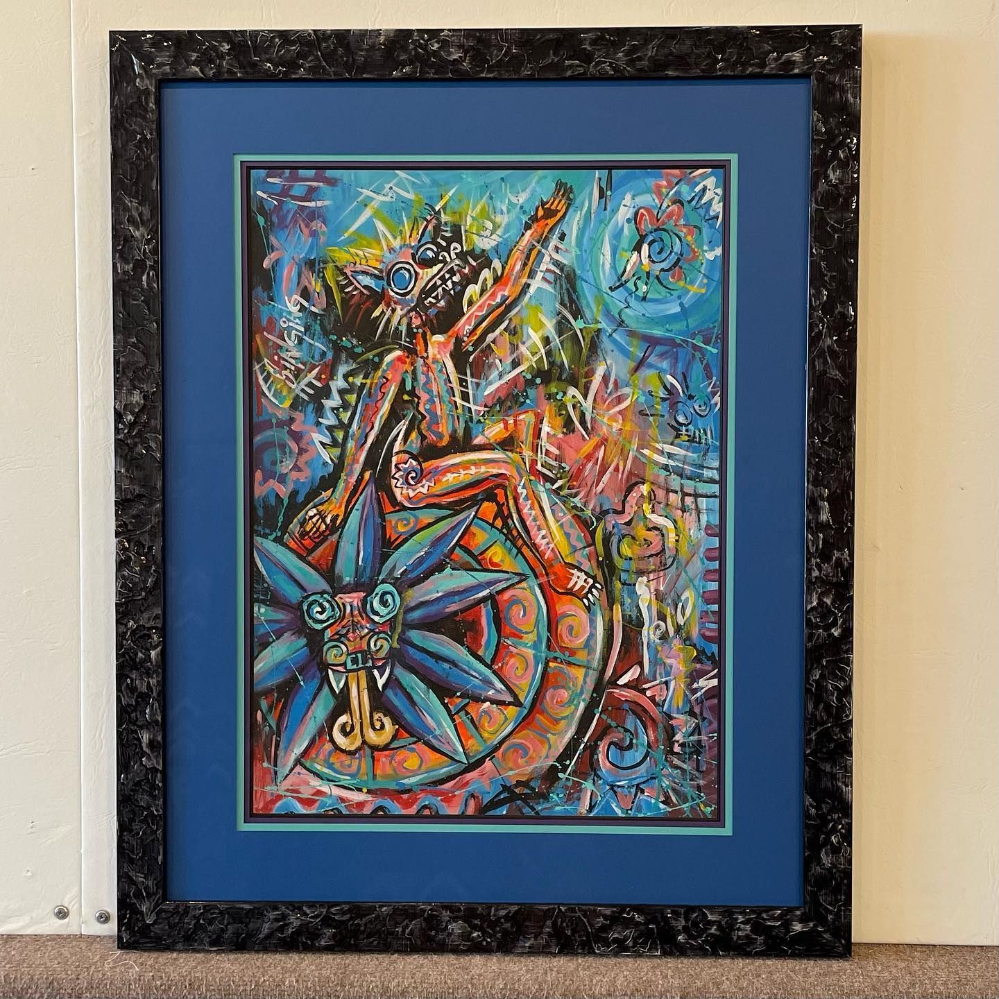 Artwork of a deity on a colorful serpent. It's framed with a blue matte and black textured frame.
