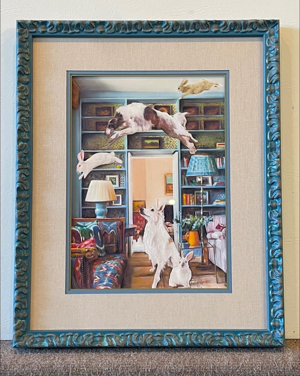 Whimsical framed artwork: dogs and rabbits jump playfully in a colorful interior, inside a teal frame.