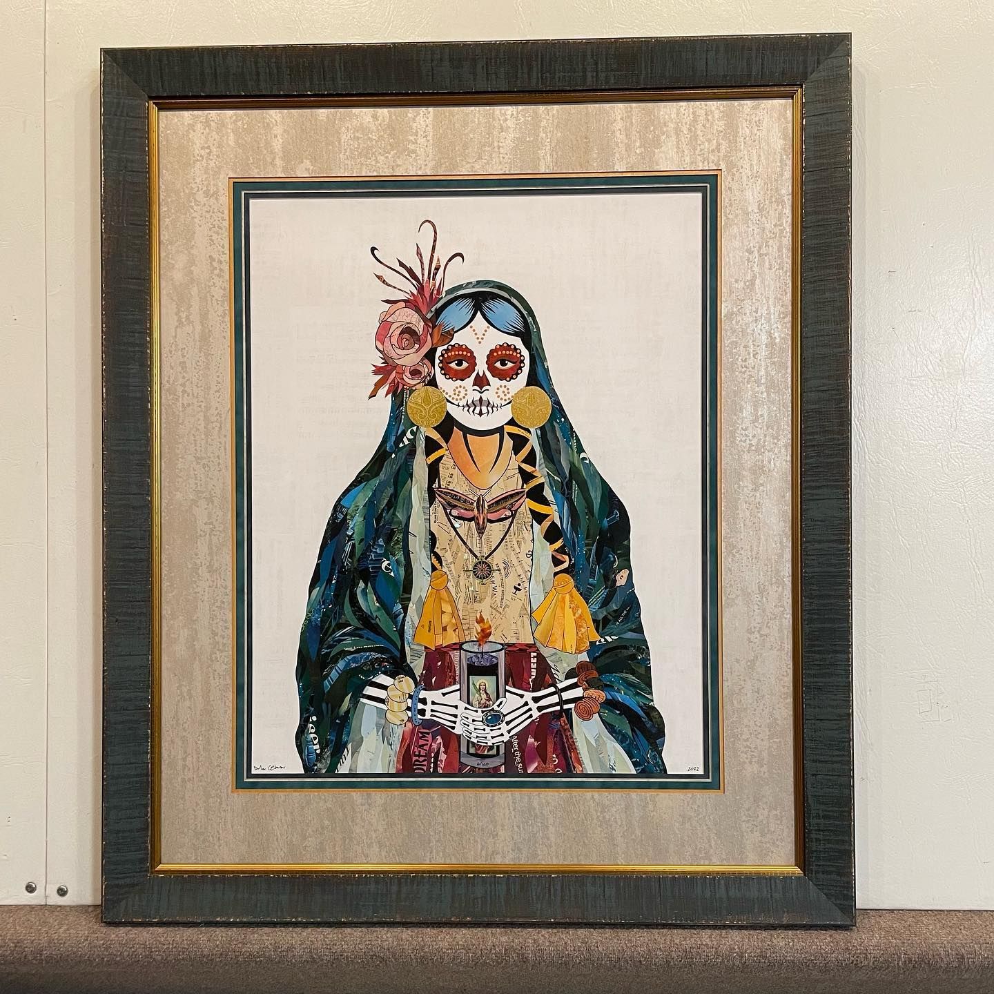 Cross-stitch Dia de los Muertos art in a framed presentation.