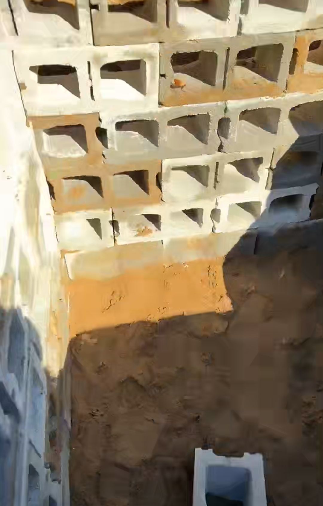 A stack of concrete blocks sitting on top of each other on a sandy surface.