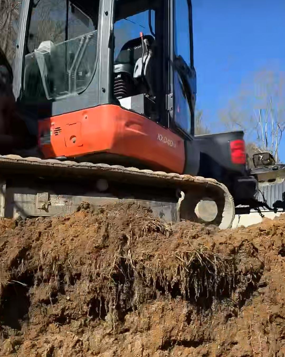 A bulldozer is driving over a pile of dirt.