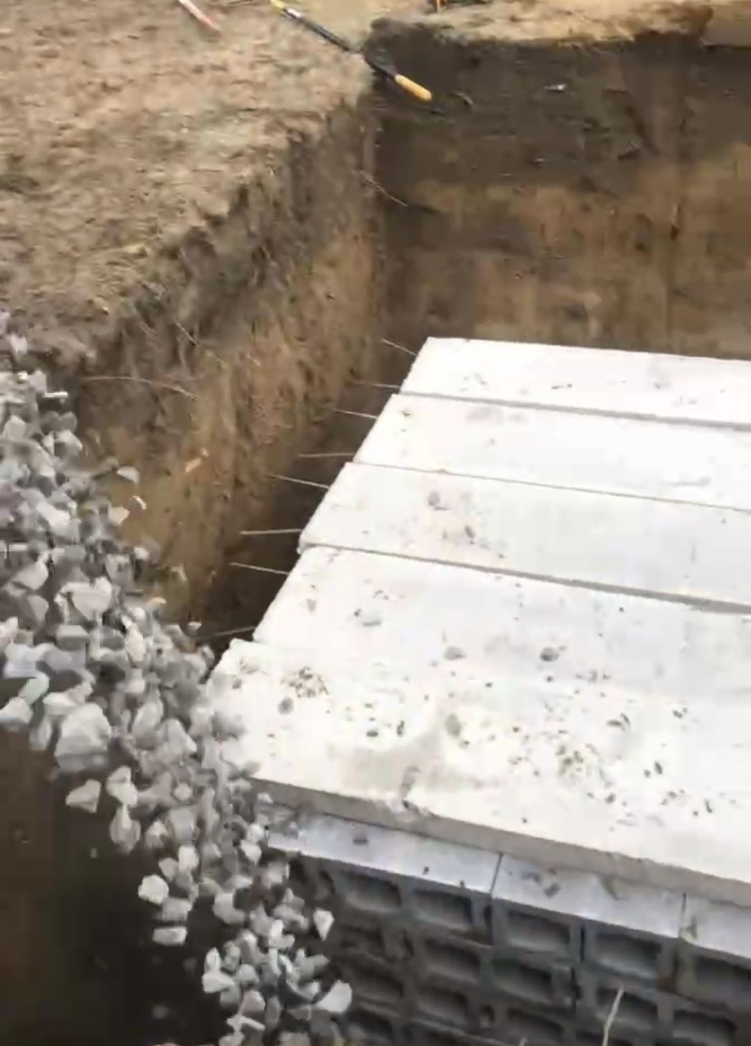 A pile of concrete blocks is sitting on top of a pile of rocks in a hole.