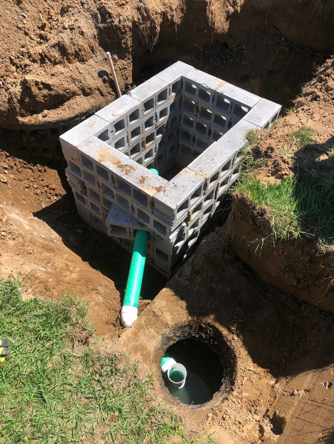 A hole in the ground with a green pipe coming out of it.