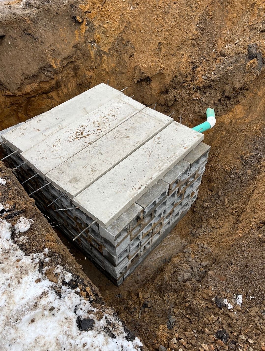 A stack of concrete slabs sitting in the dirt next to a pipe.
