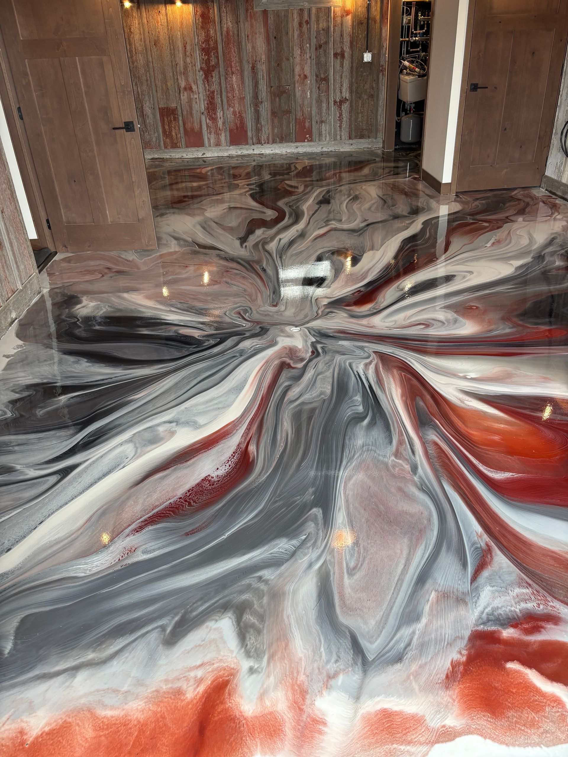Abstract metallic swirl floor art in silver, gray, and red inside a room