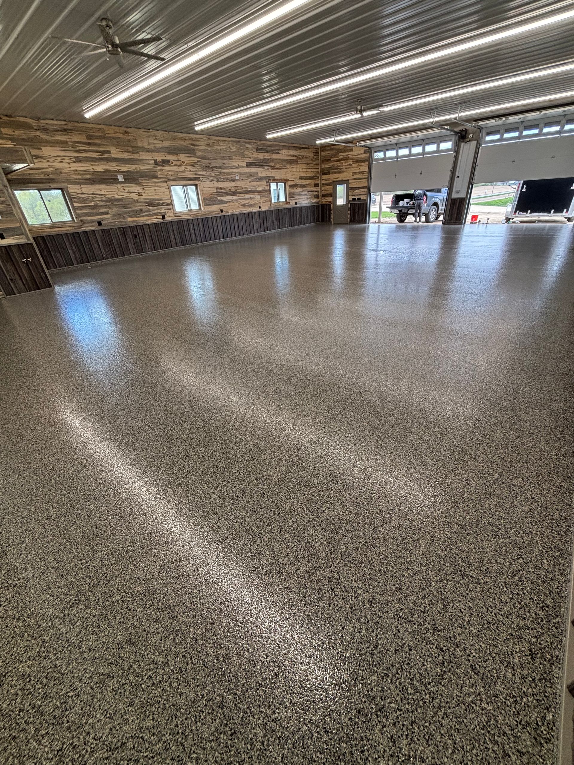 Empty indoor warehouse with polished speckled floor, brick walls, and bright overhead lights
