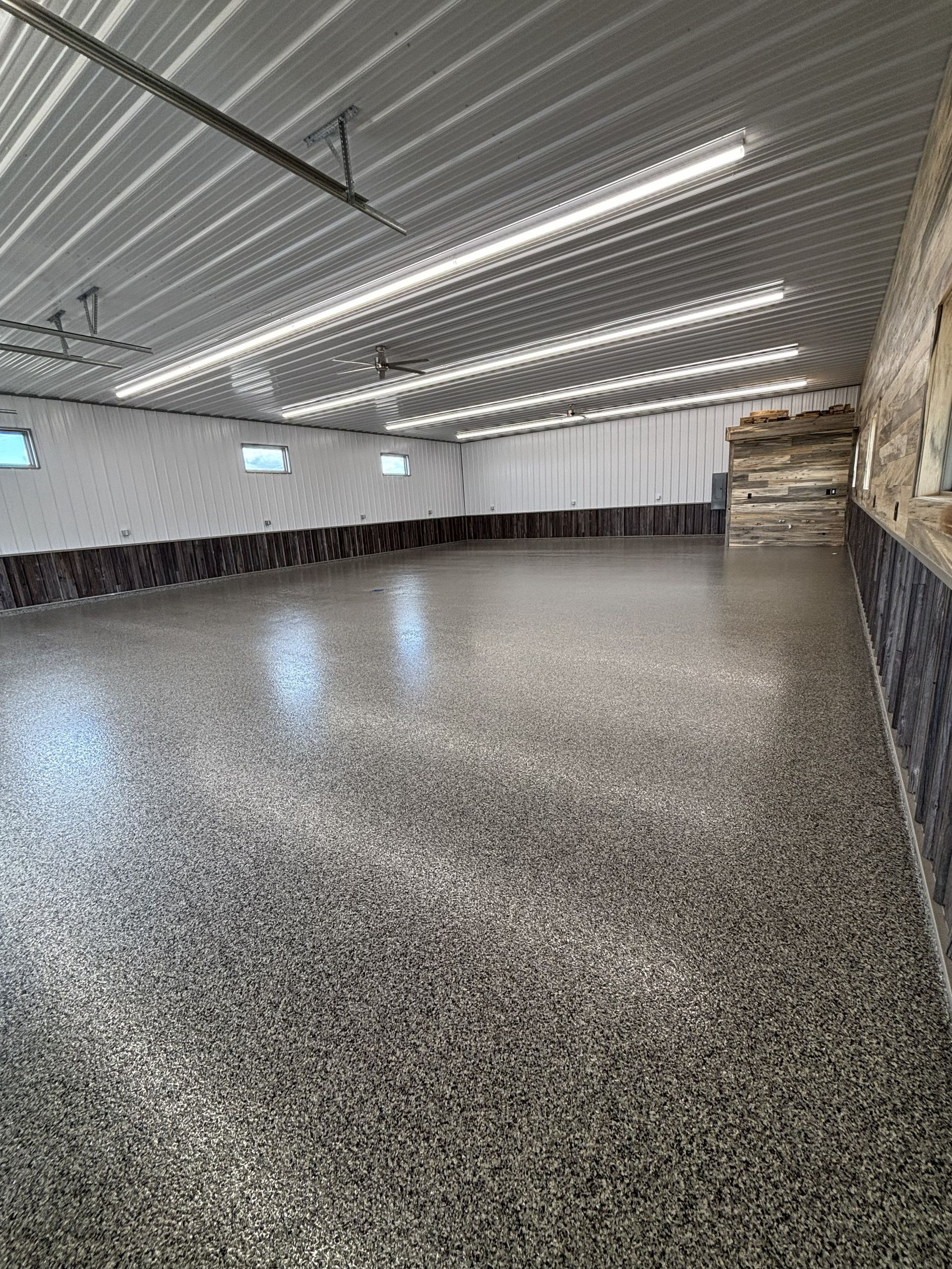 Empty indoor sports hall with speckled floor, bright overhead lights, and benches along the wall
