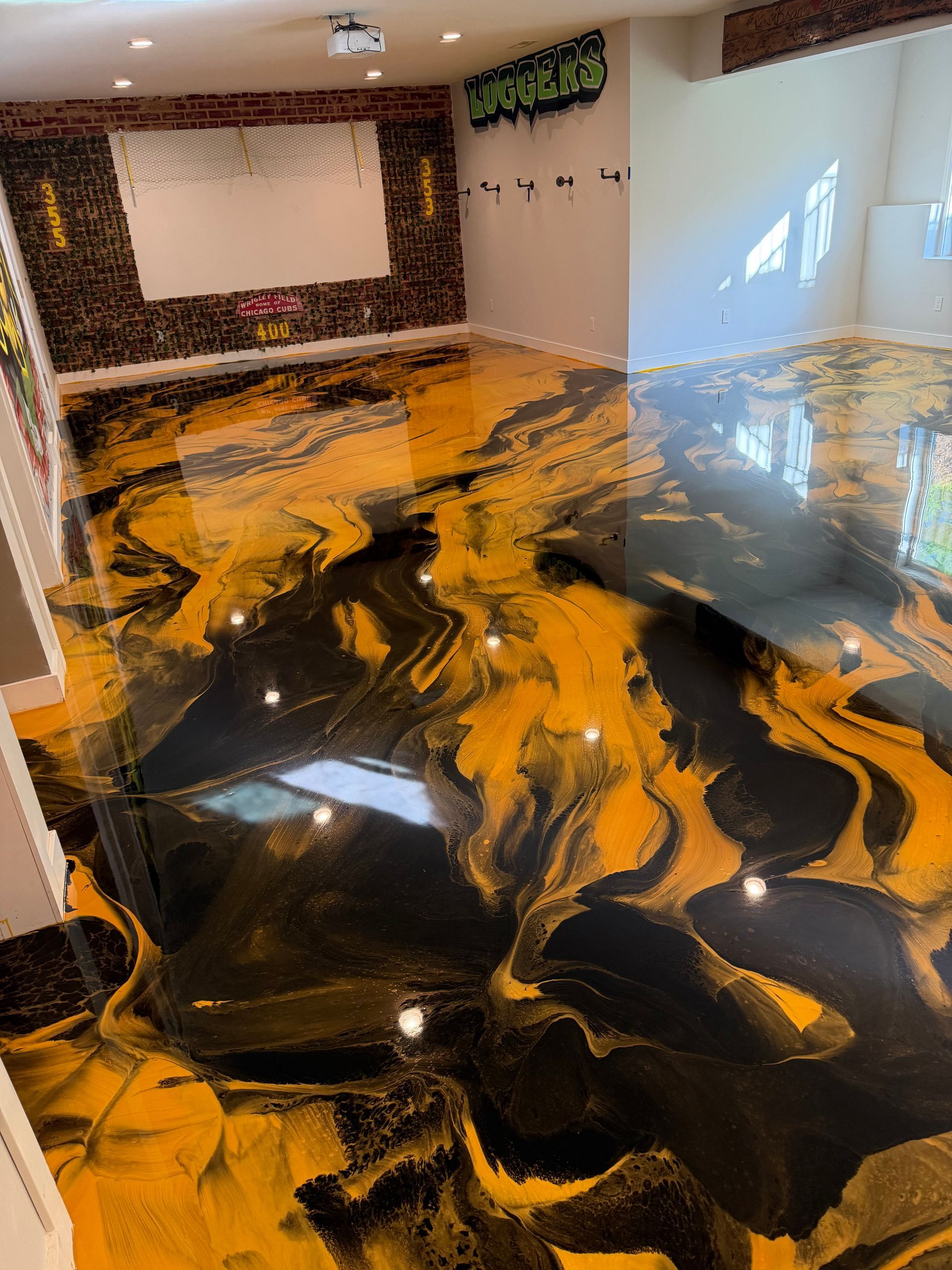 Abstract black and gold epoxy floor in a room with a projector screen and wall-mounted TV
