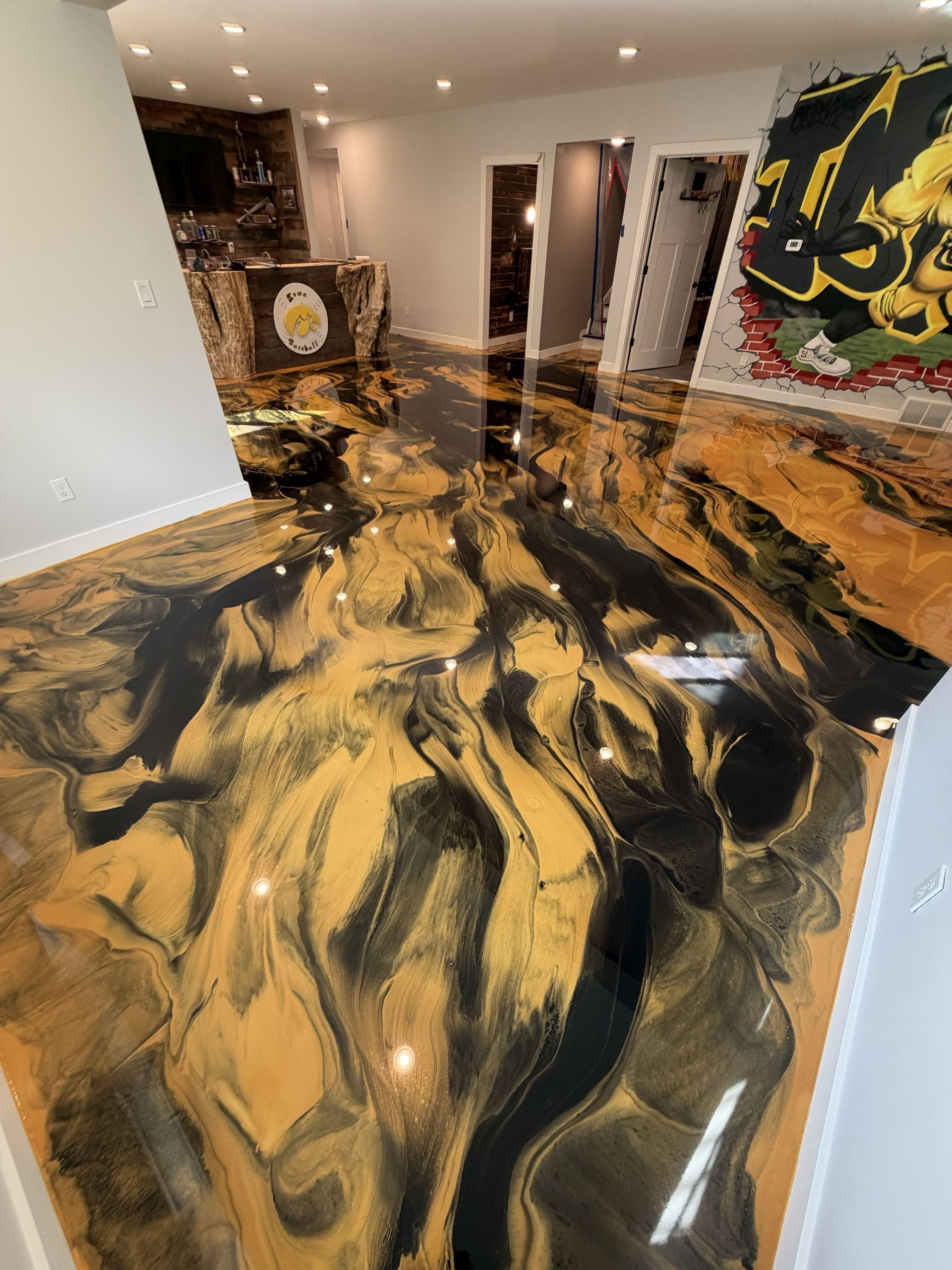 Black and gold marbled epoxy floor in a modern room with white walls and wall art