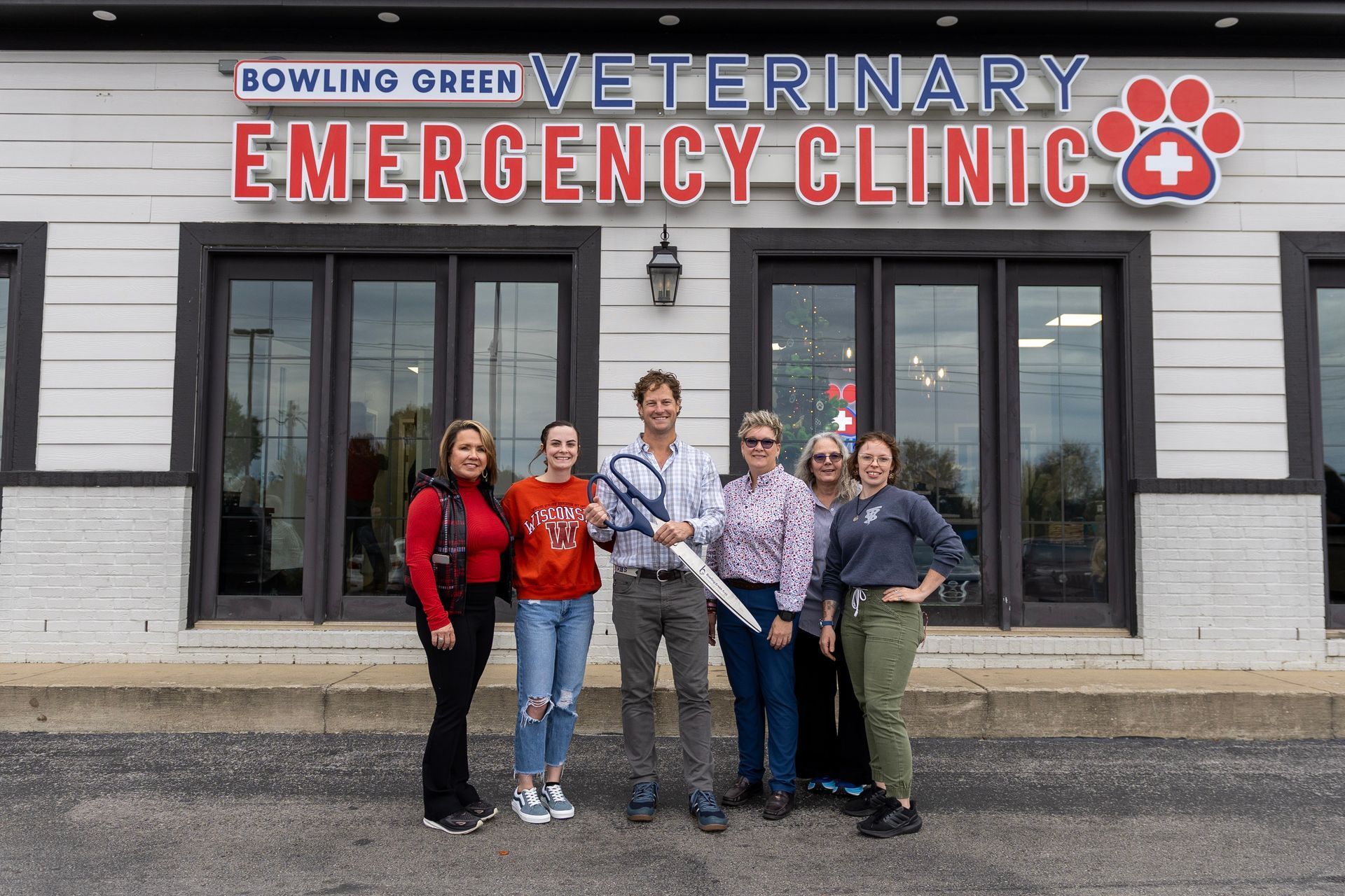 A group of people are standing in front of a veterinary emergency clinic.