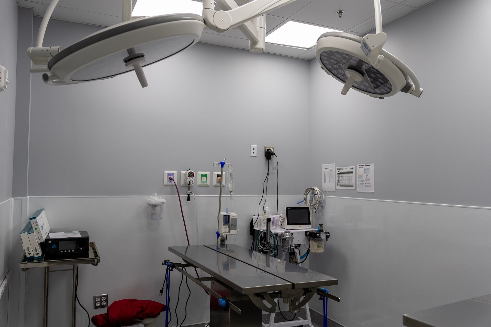 An empty operating room with two surgical lights and a table.