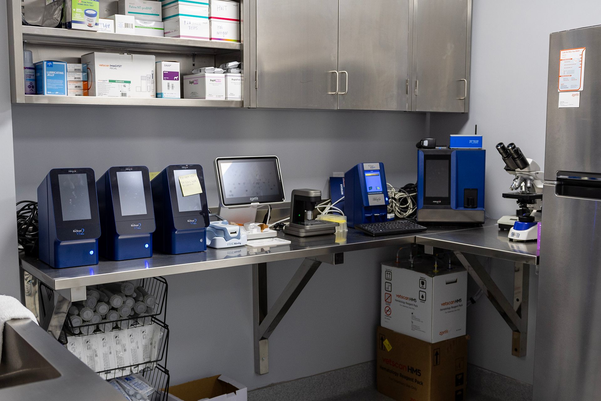 A stainless steel lab with a desk, computer, microscope, and refrigerator at Bowling Green Veterinary Emergency Clinic.