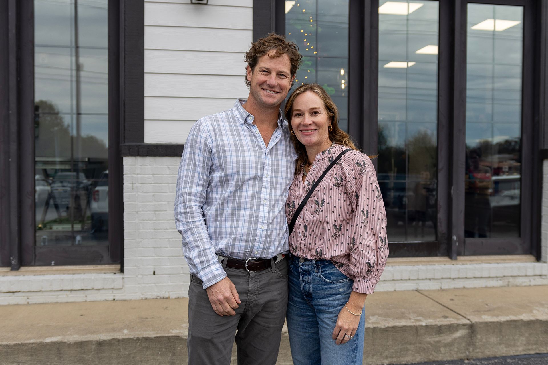 A man and a woman are posing for a picture in front of Bowling Green Veterinary Emergency Clinic.