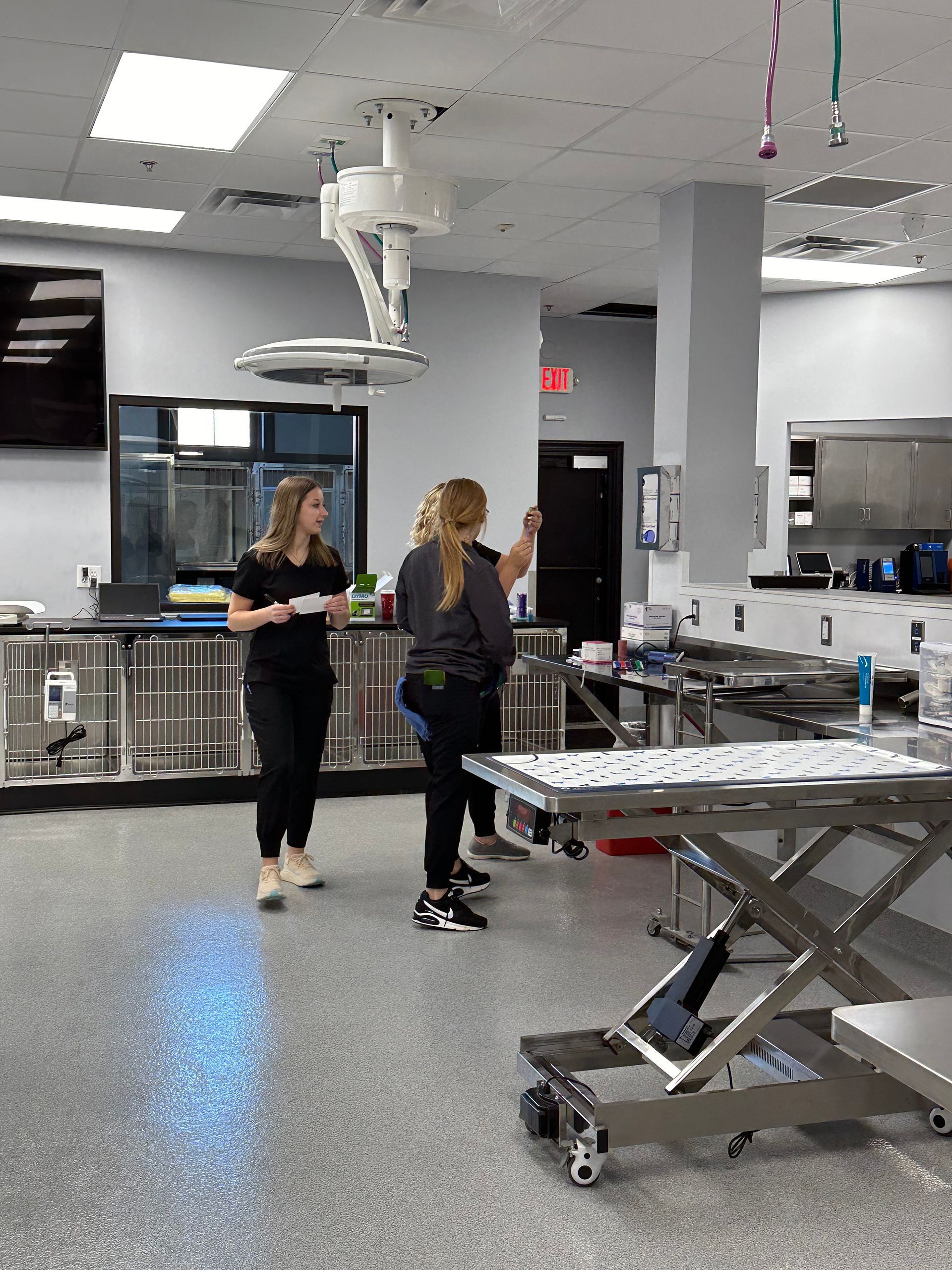 Two women at Bowling Green Veterinary Emergency Clinic are standing in an operating room talking to each other.