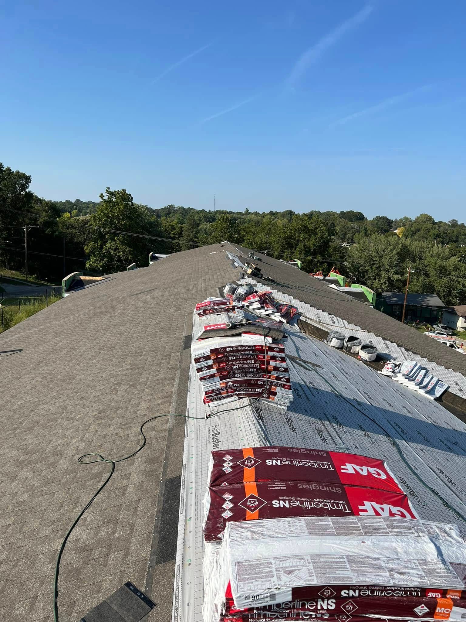 A sloped roof with red and white covering under a clear blue sky, surrounded by trees.
