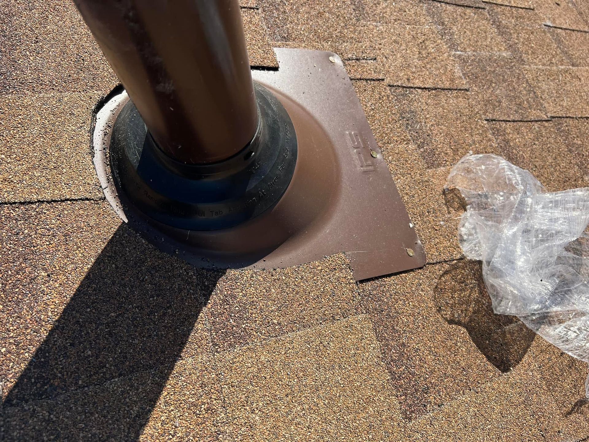 Roof vent pipe flashing on a shingled roof with sealant around the base