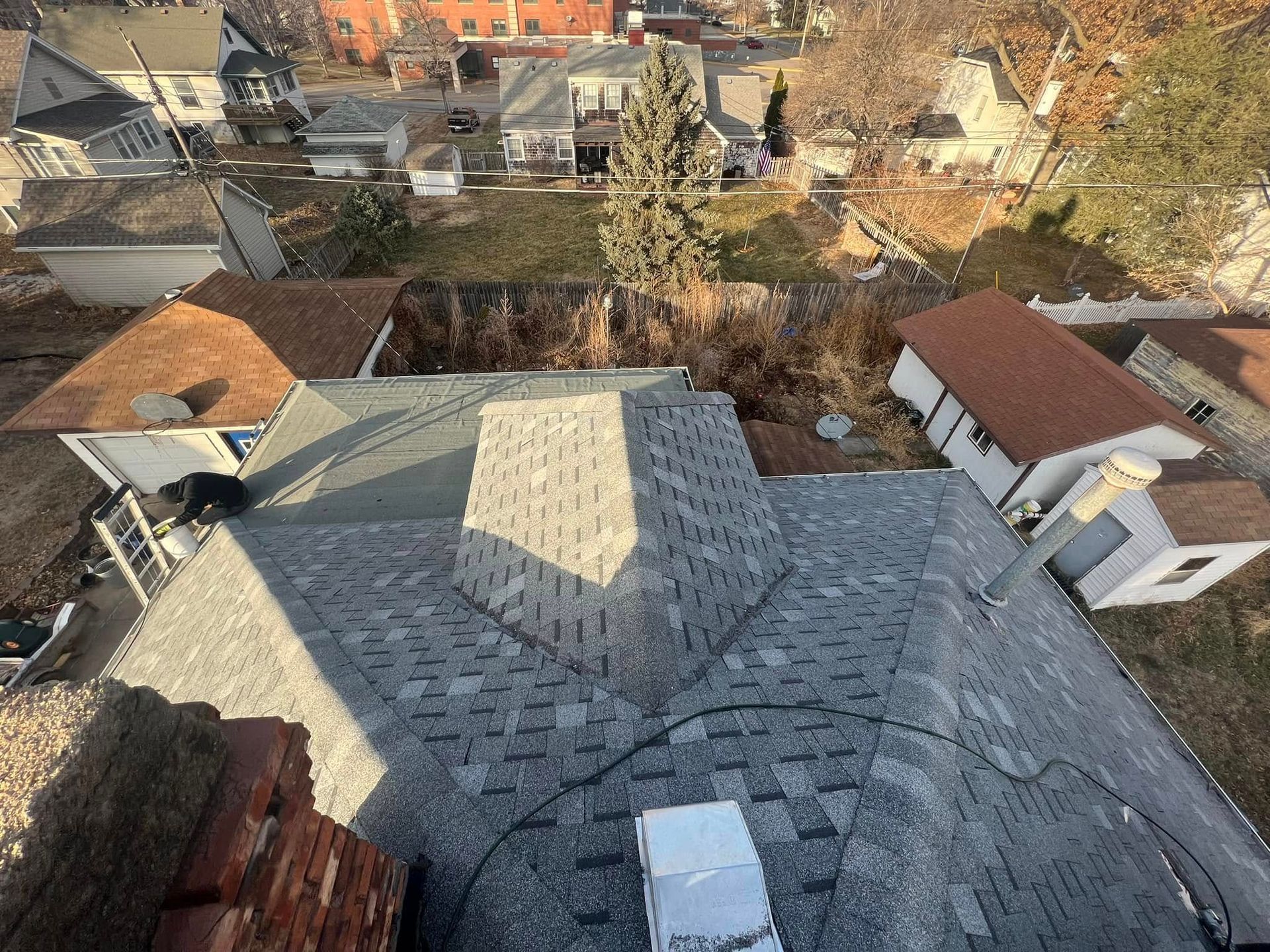 View from a rooftop over a neighborhood of houses and trees in daylight.