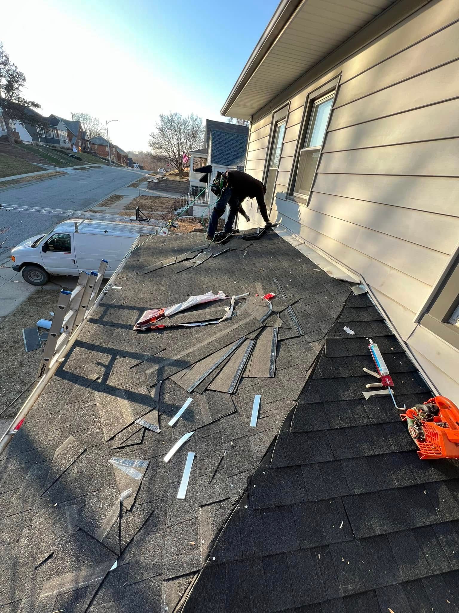 Person working on a rooftop beside a beige house, with tools and debris scattered around.