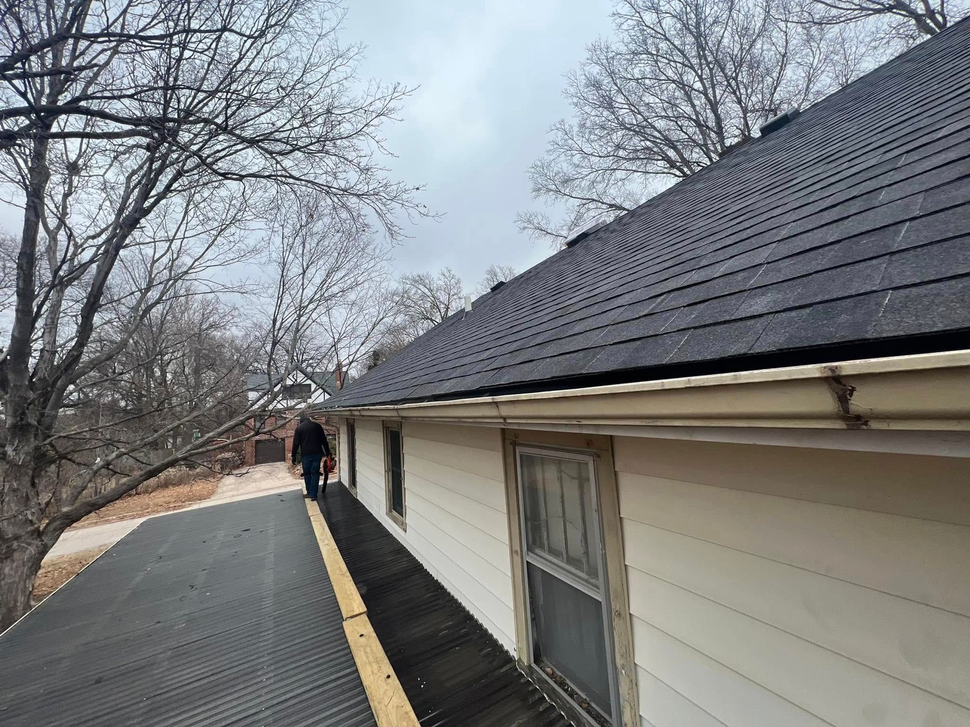 Long, narrow rooftop walkway beside a cream building, with bare trees and a person in the distance.