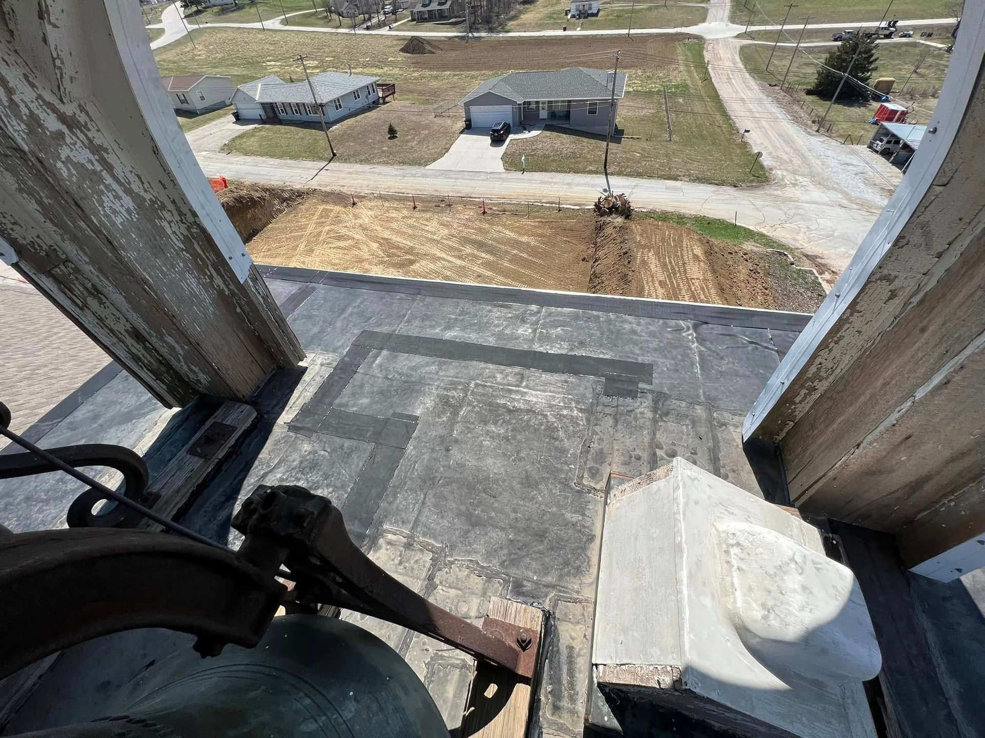 View from a building window frame onto a yard with paths, grass, and a sidewalk below.