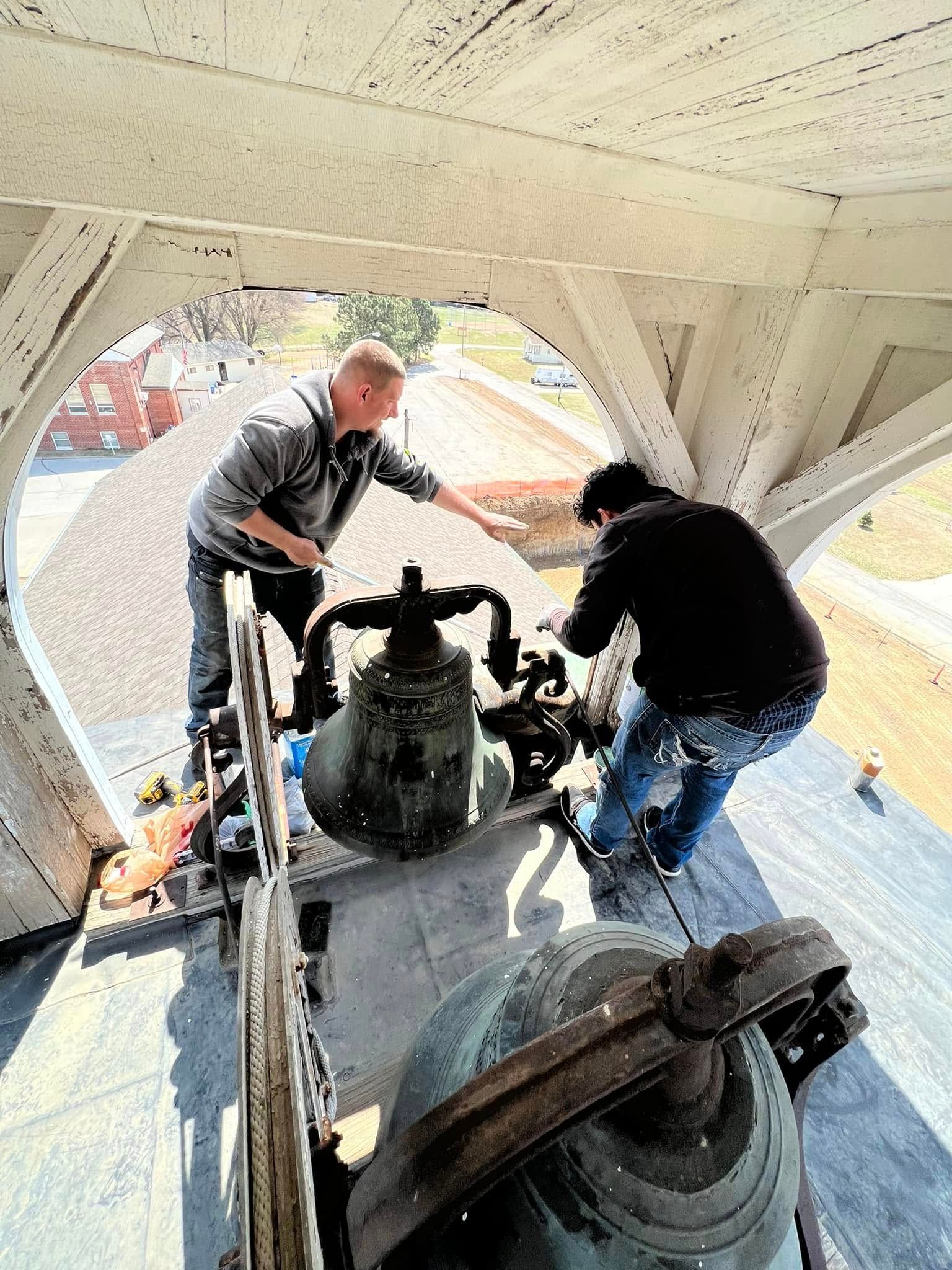 Two workers inspecting machinery inside a large white industrial structure with a view outside.