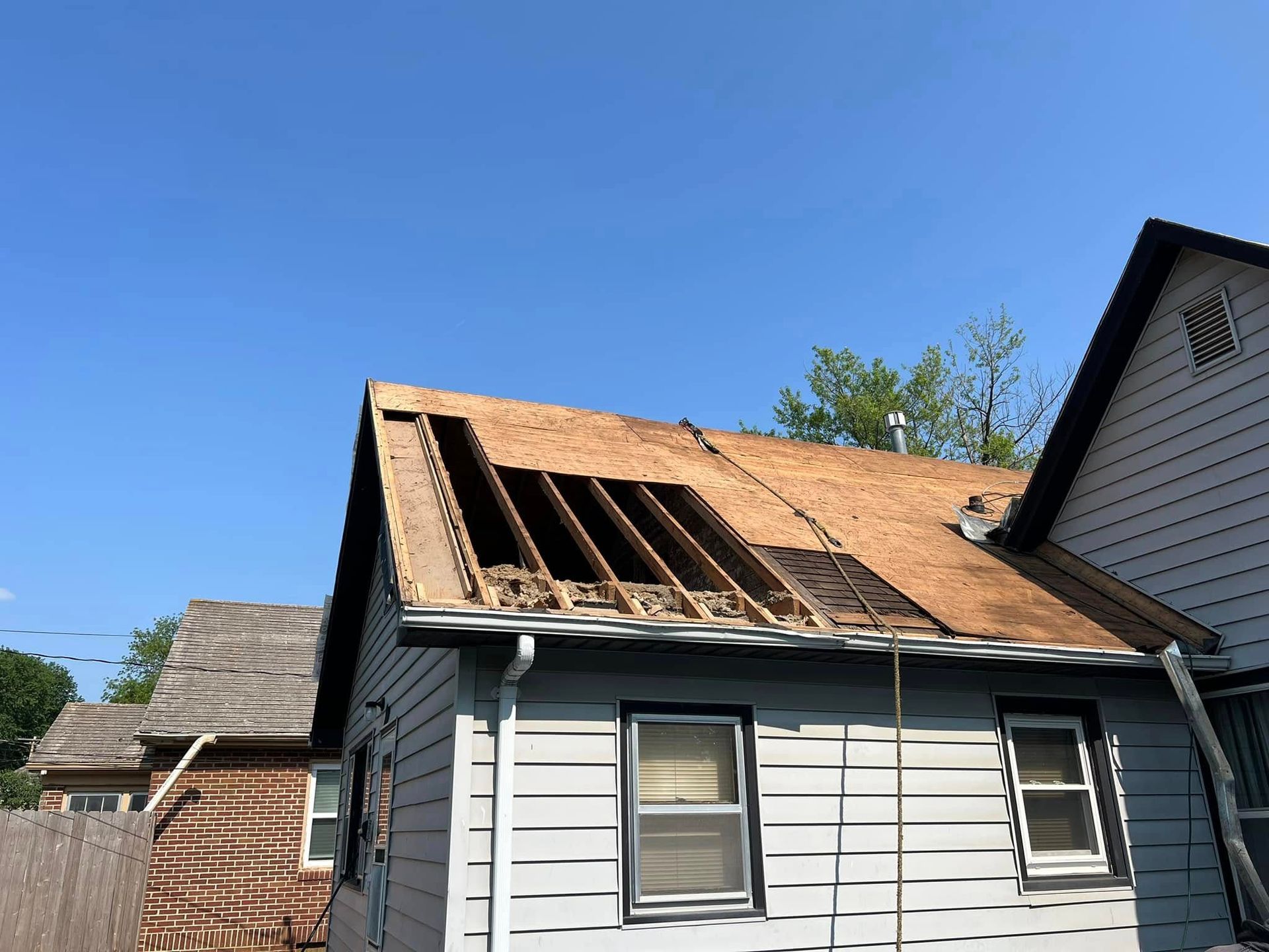 House with roof under repair, exposed wooden rafters and blue sky above