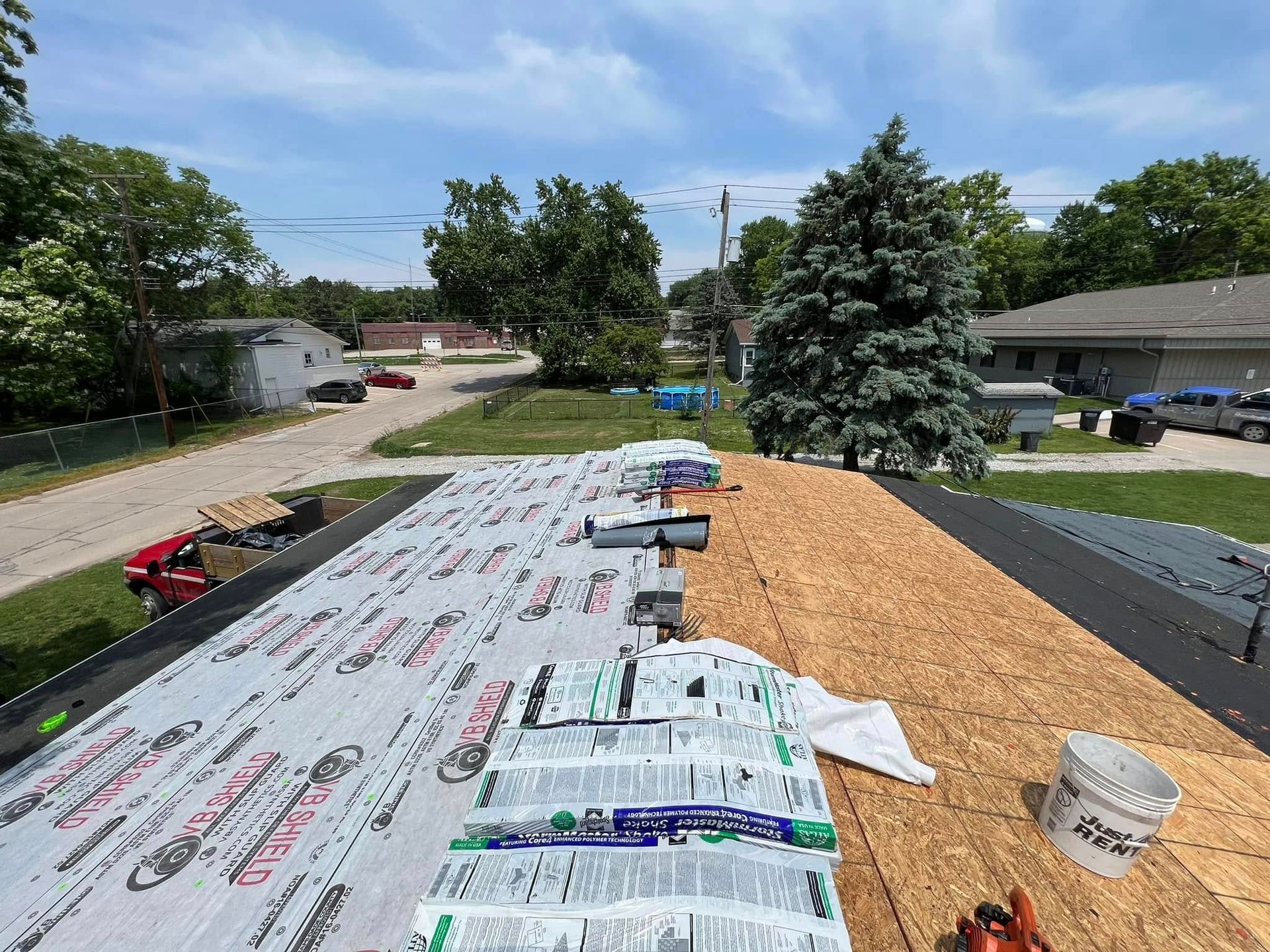 Roof under construction with underlayment and wood shingles in a suburban neighborhood