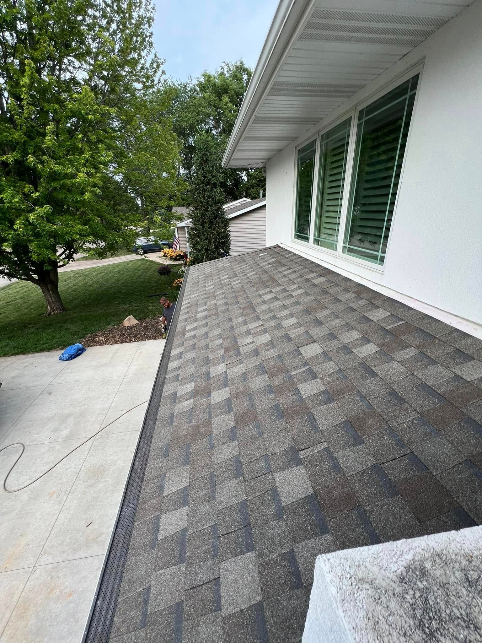 House exterior with gray shingle roof, white siding, green shutters, and a driveway beside trees