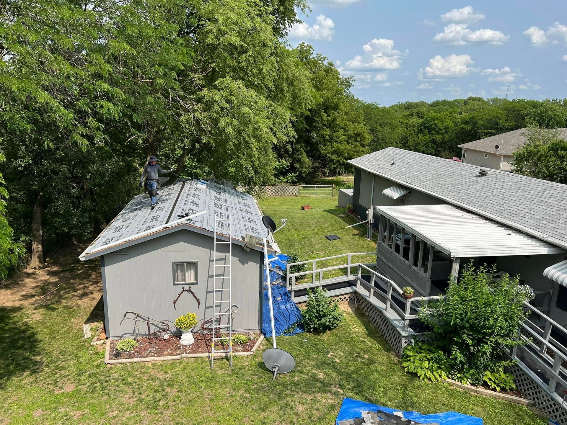 Backyard with a small shed, deck, and house surrounded by trees and greenery