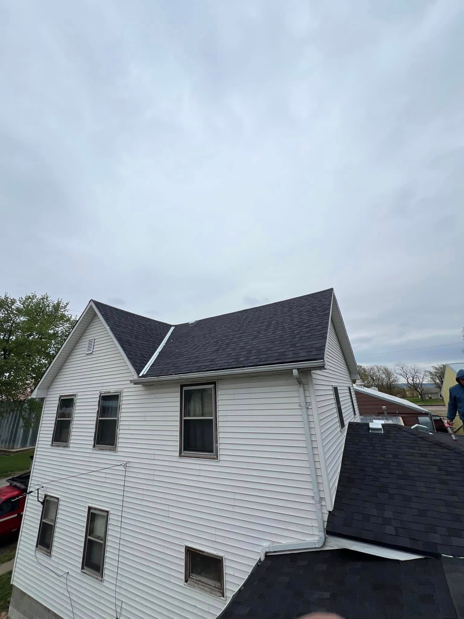 Damaged white house with a partially collapsed roof under a cloudy sky