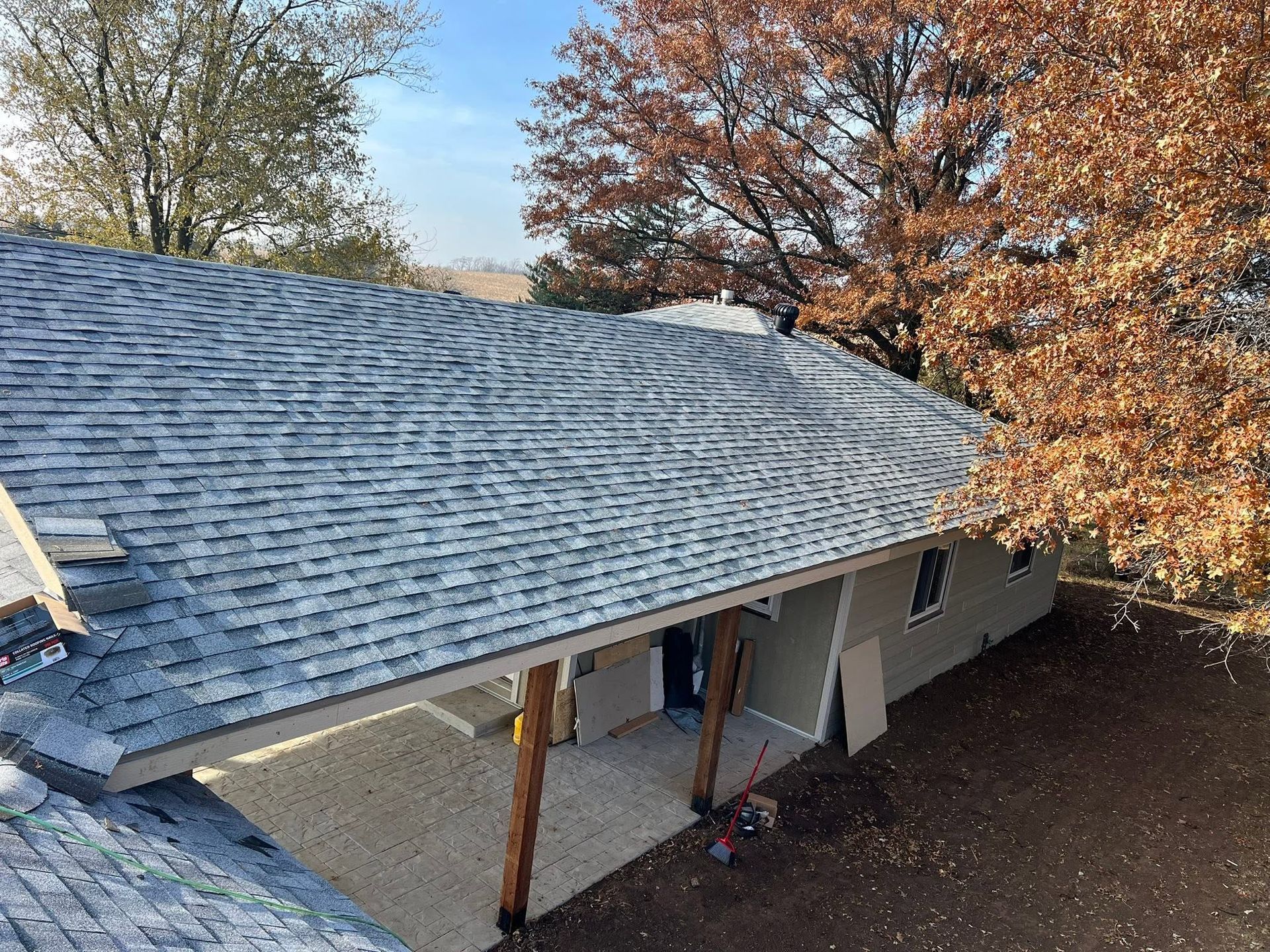 Roofing work on a house with gray shingles and workers near the front entrance