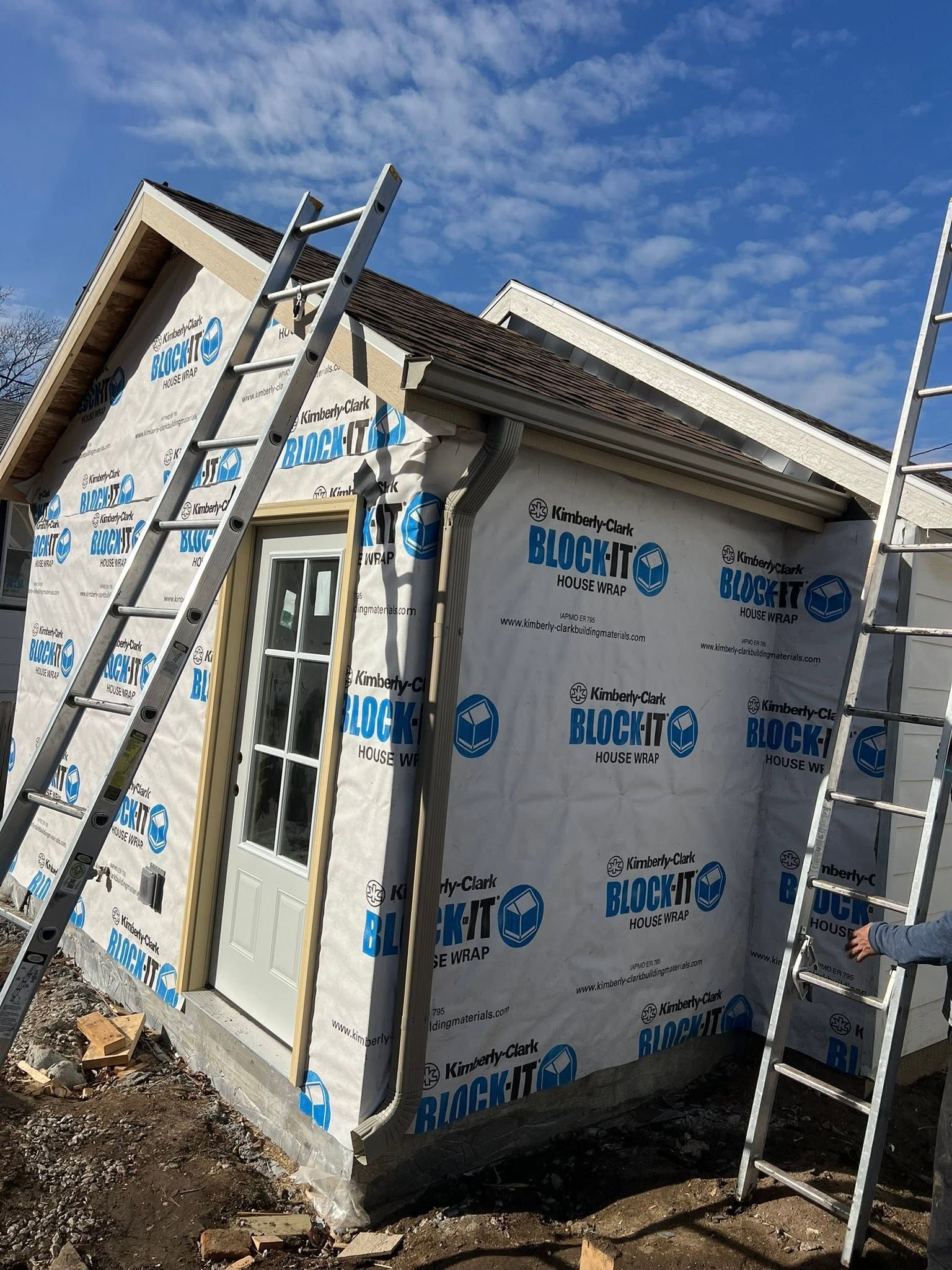 Insulated shed under construction with ladders leaning against the walls under a blue sky