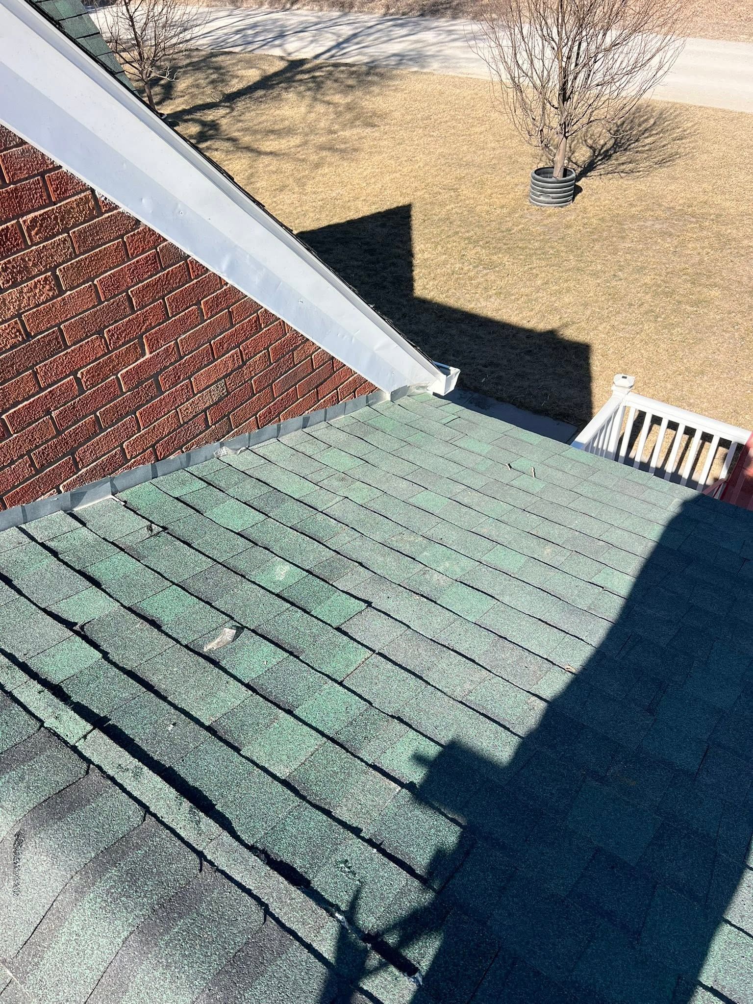 Roofing shingles and siding with a sharp shadow on a house roof, viewed from above