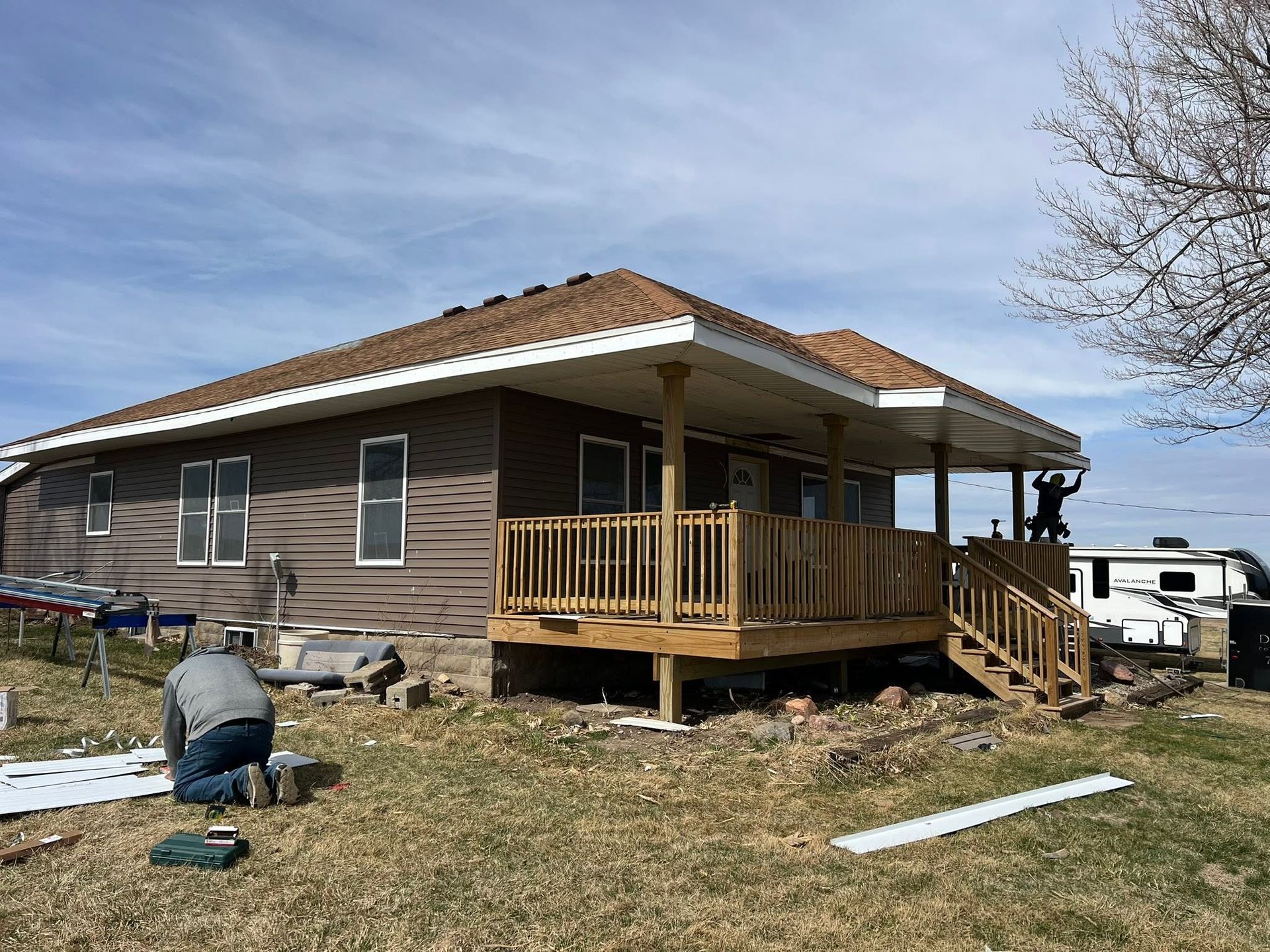 Single-story house with wood siding and porch under construction on a grassy lot
