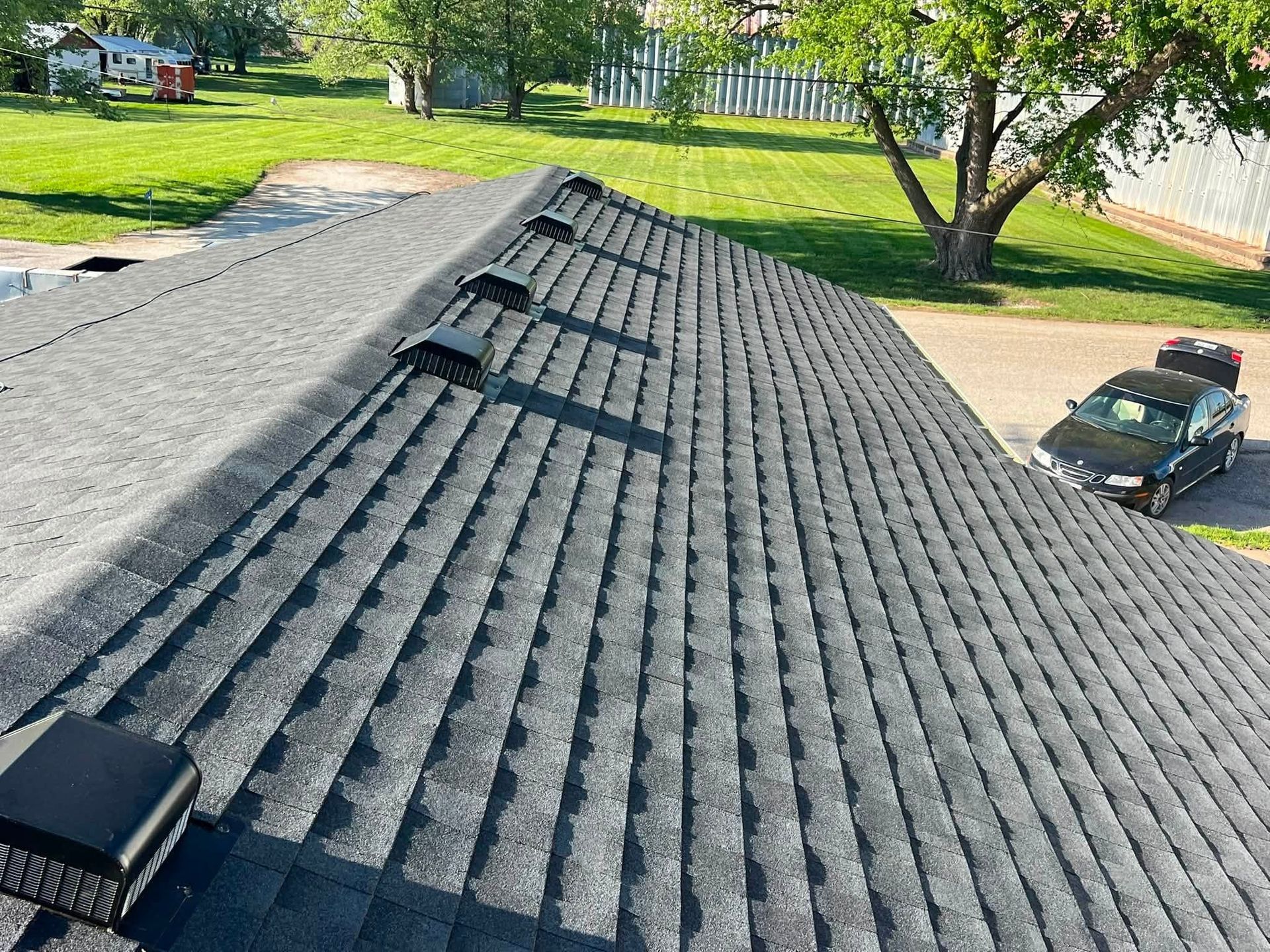 Gray shingled roof with skylights and vents in a residential neighborhood, viewed from above
